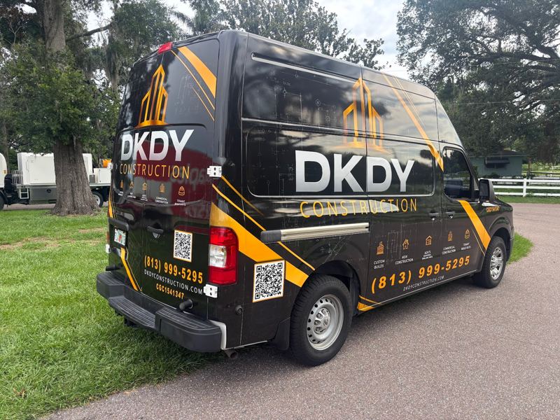 Black cargo van with a gold and black construction company wrap
