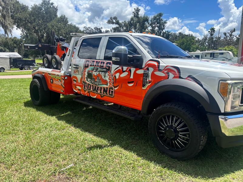 Ford wrecker tow truck with an orange and white towing company wrap
